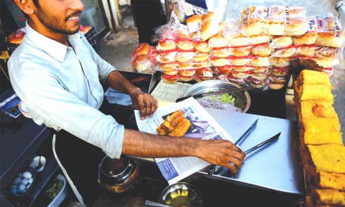 Food being packed in newspaper by a street vendor