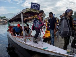 Foreign tourists disembark from a boat on the banks of Dal Lake as they prepare to leave Srinagar on August 03, 2019