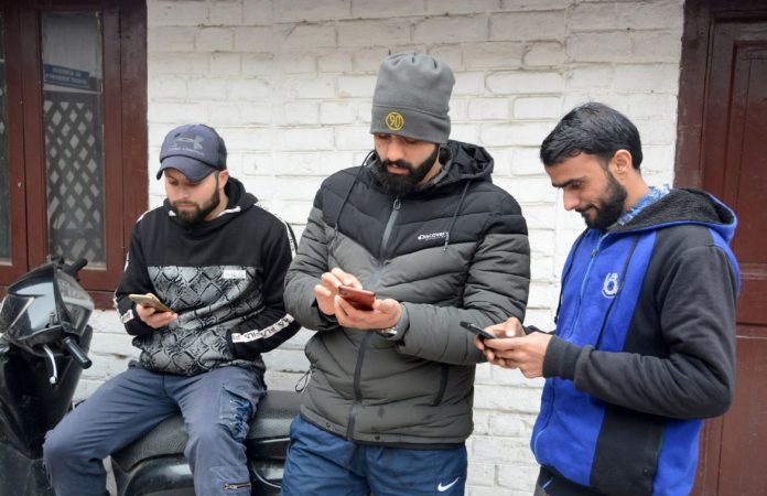 Youth surfing internet in Srinagar after Govt restored 2G internet after over 5 months