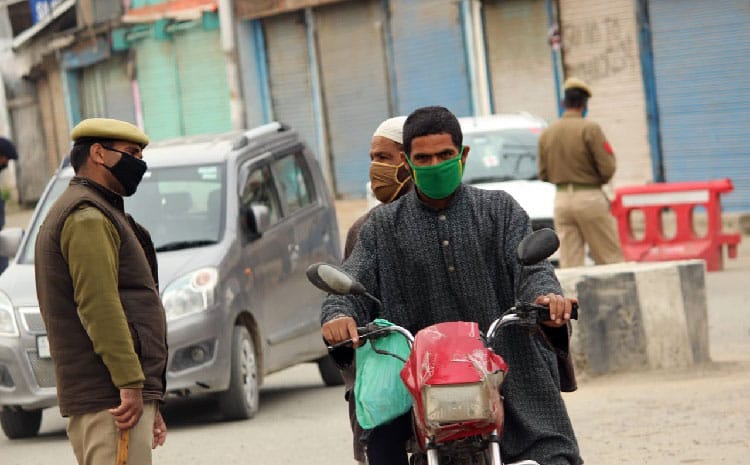 Amid lockdown, a motorcyclist rides past a barricade in Pulwama town