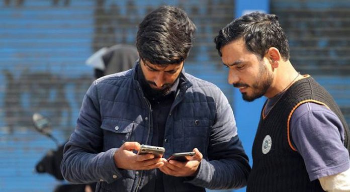 Youth accessing internet on their phones in Srinagar