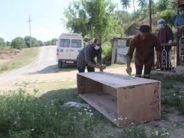 Local people help the medical team at Tujan village in Pulwama for making a casket for the deceased victim