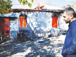 A man looks on as a house burns in the village of Charektar