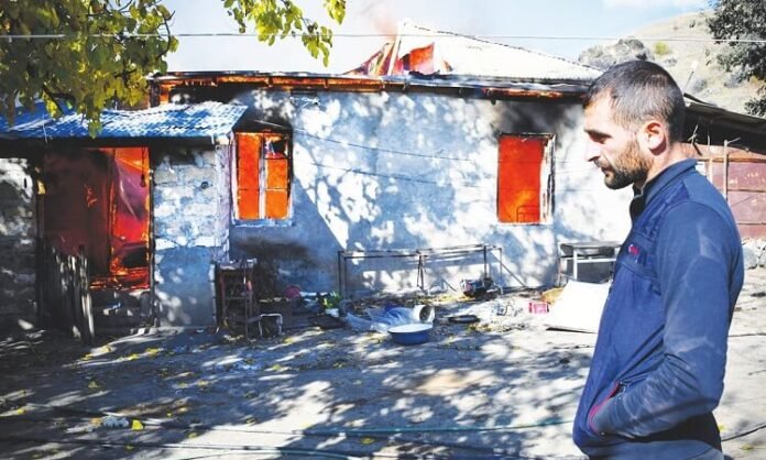 A man looks on as a house burns in the village of Charektar A man looks on as a house burns in the village of Charektar