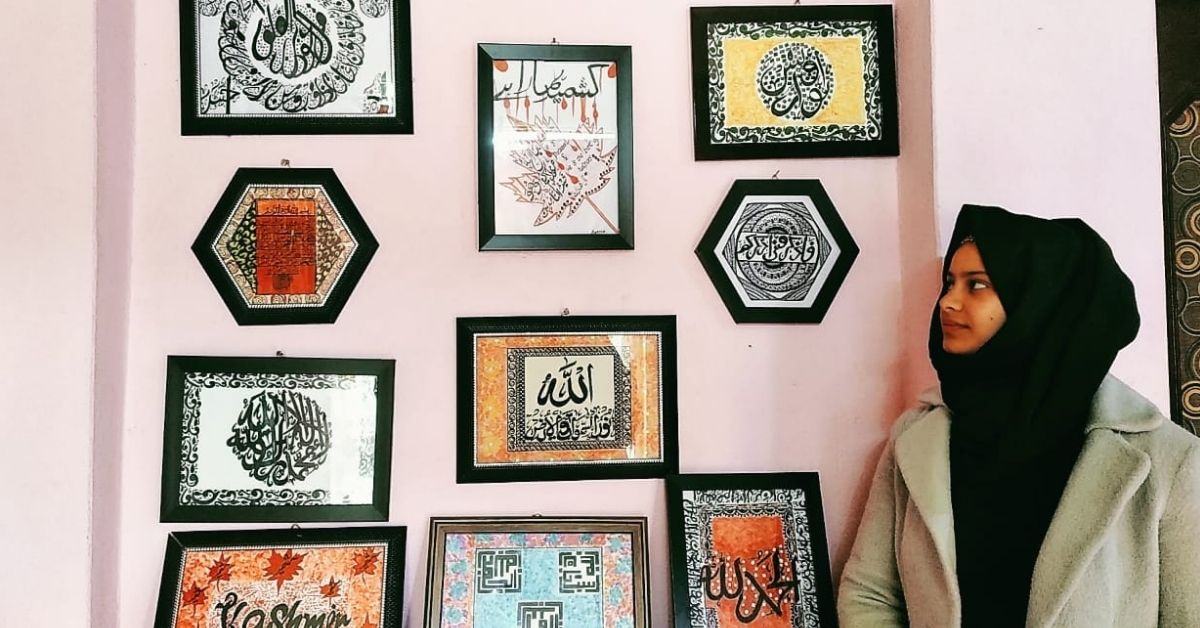 Aabida Rashid looks on, with her art pieces hung on a wall