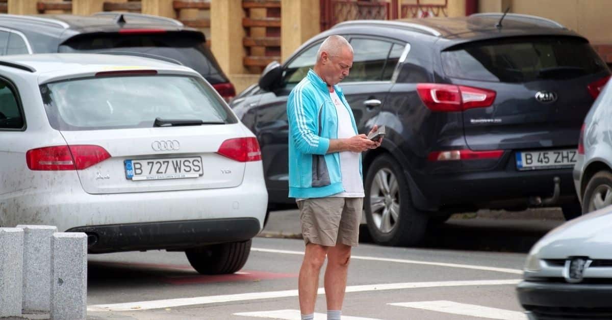 Man using his smartphone near parked cars