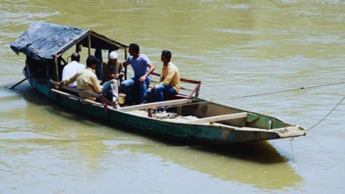 People cross Jhelum in a boat due to delayed construction of bridge in Pulwama