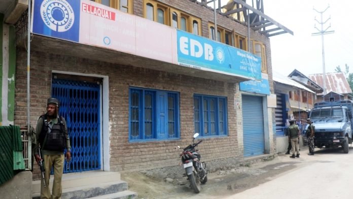 Security personnel stand guard outside Ellaqie Dehati Bank in Kulgam