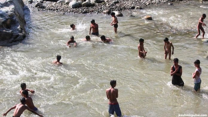 Children taking bath to beat the heat in a canal in south Kashmir's Pahalgam area Children taking bath to beat the heat in a canal in south Kashmir's Pahalgam area