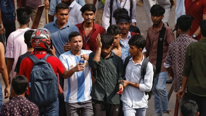 An injured student walks during a clash in Bangladesh