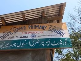 Pulwama’s young students endure scorching heat as school construction stalls School Signboard Clinging to a Tin Shed