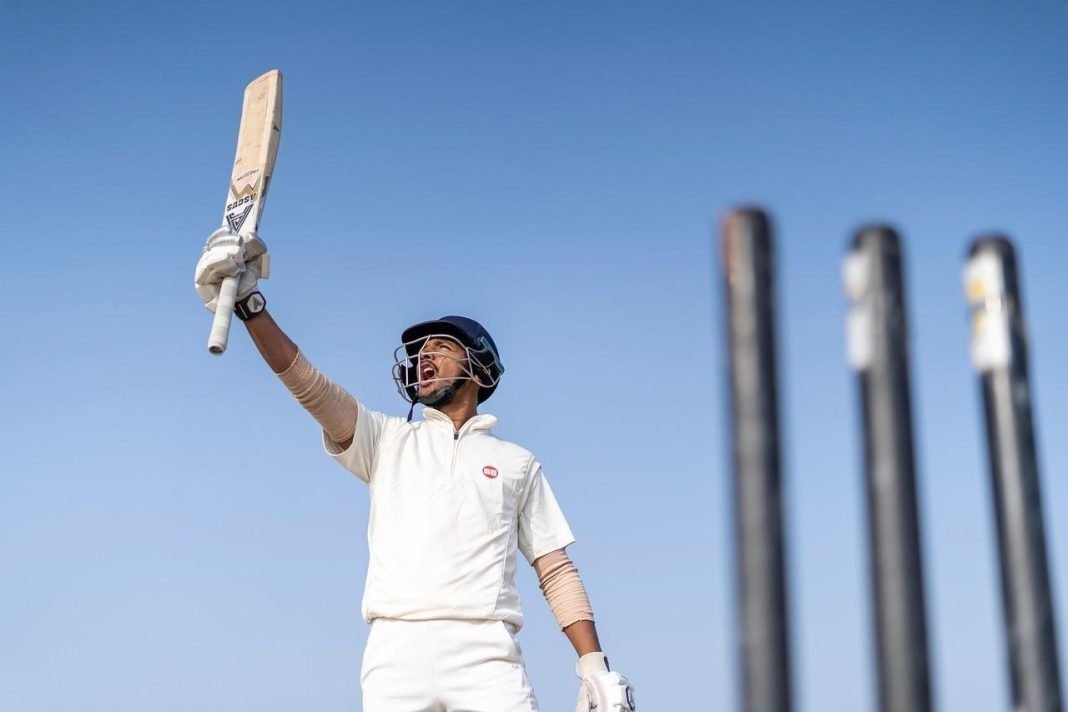 A young cricketer waving his bat to the spectators after achieving a feat A young cricketer waving his bat to the spectators after achieving a feat