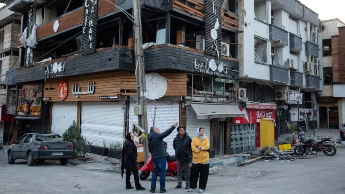 People gathered at a corner in Tehran, near a building showing substantial damage People gathered at a corner in Tehran, near a building showing substantial damage.