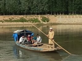 In absence of a bridge, people rely on wooden boats to cross the river