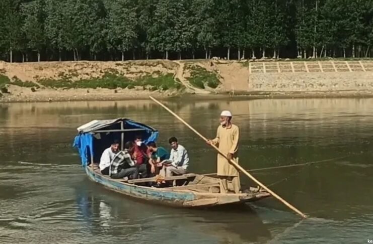 In absence of a bridge, people rely on wooden boats to cross the river